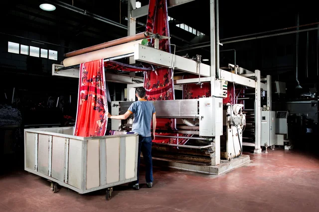 Pria pekerja sablon mengontrol proses printing pada kain kaos (Foto: Pexels / Engin Altundağ)