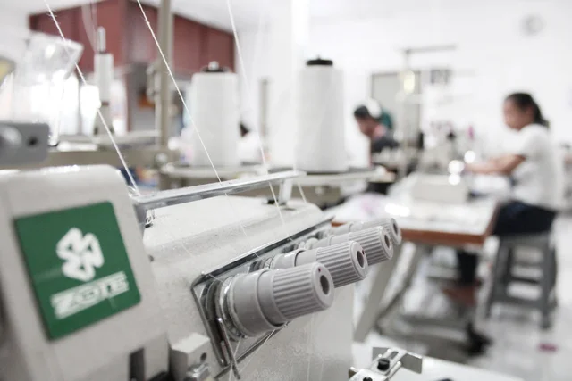 Detail mesin jahit di workshop konveksi tekstil untuk produksi kaos lengan panjang custom